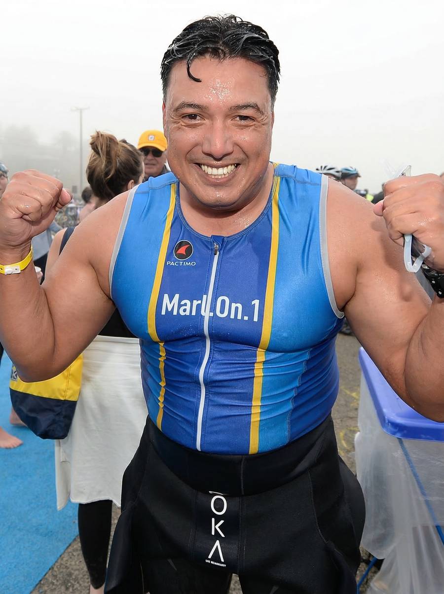 Marlon flexing after ocean swim in Marl.On.1 jersey, fists raised