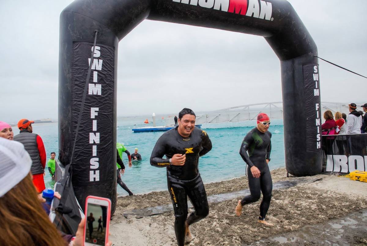 Marlon crossing Ironman swim finish arch with big smile