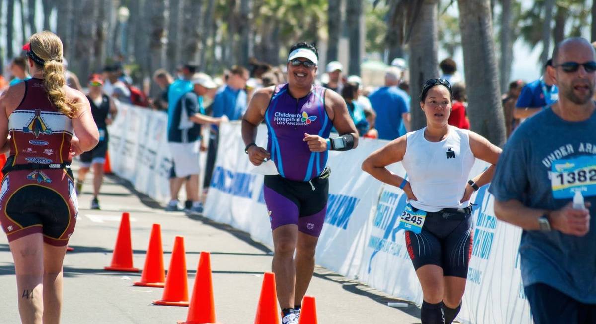 Marlon running triathlon in CHLA jersey among palm trees