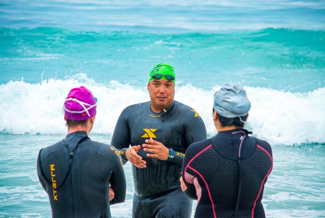 Coach Marlon face to face with athletes in the ocean surf giving instructions