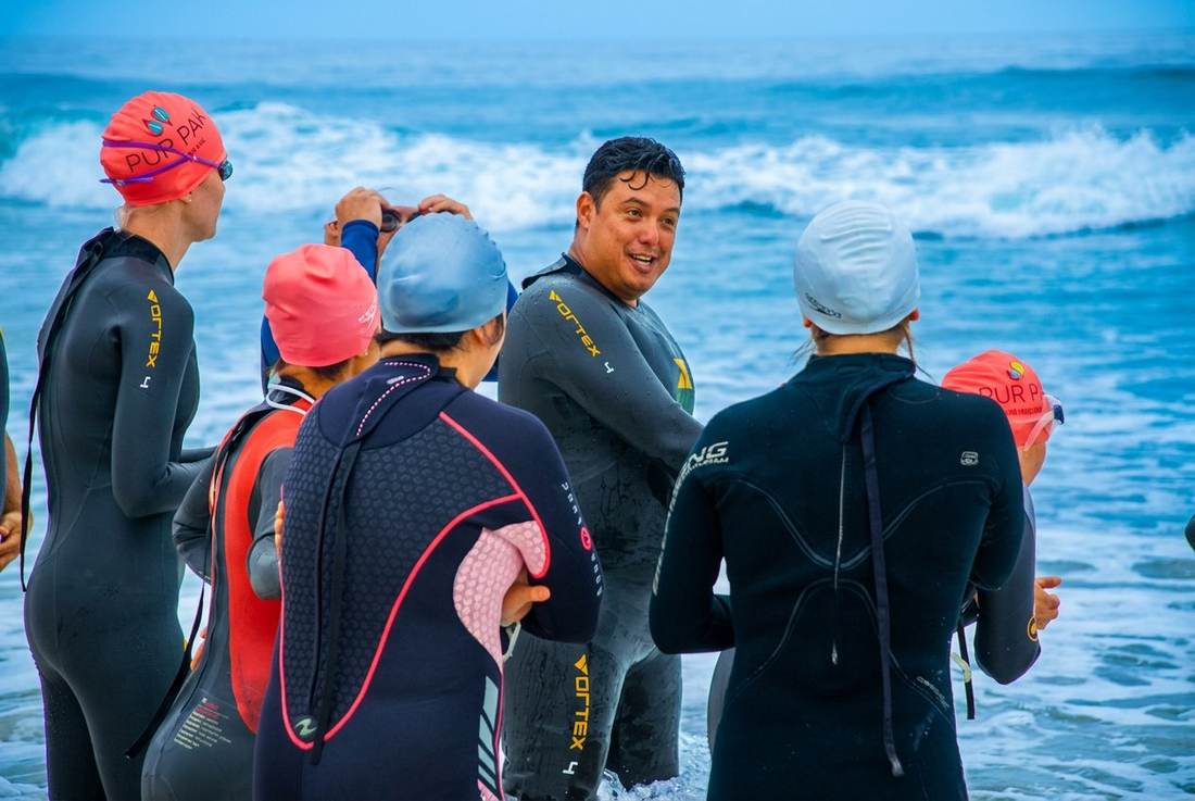 Marlon coaching group surrounded by athletes in the ocean