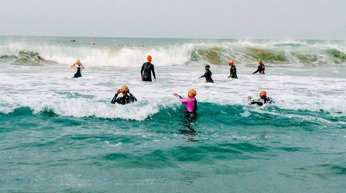 Athletes navigating rough surf and waves during ocean swim session