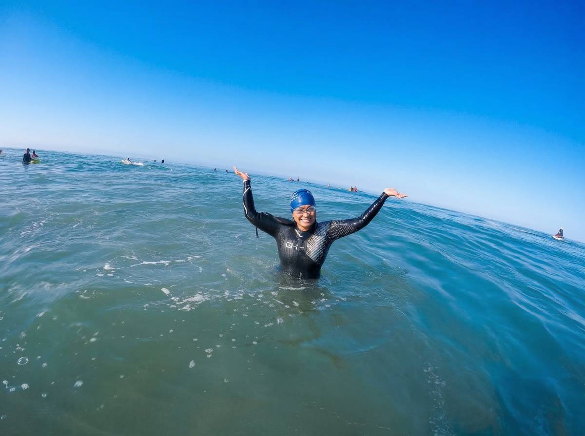 Athlete arms raised celebrating in the ocean after completing open water swim