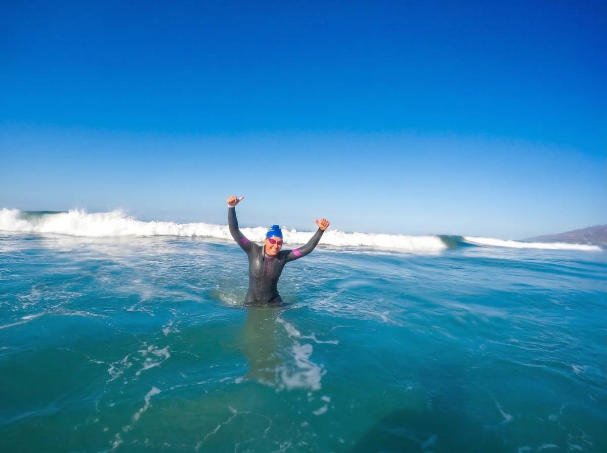 Athlete giving double thumbs up in waves after conquering ocean swim