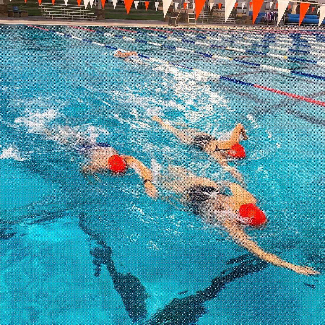 Red cap swimmers racing in outdoor pool