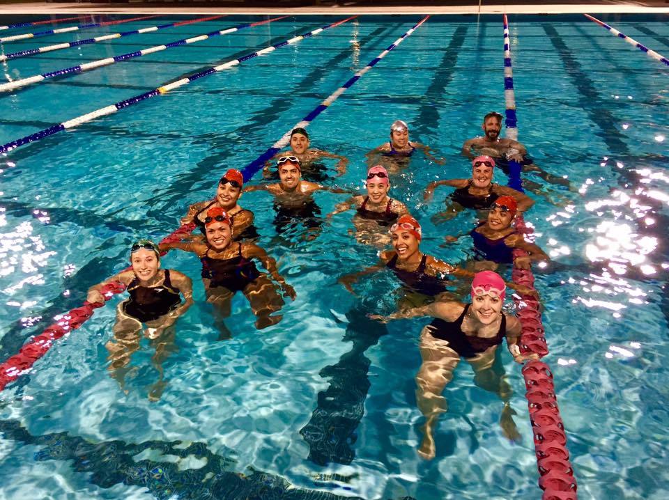 Team smiling in pool after night swim session