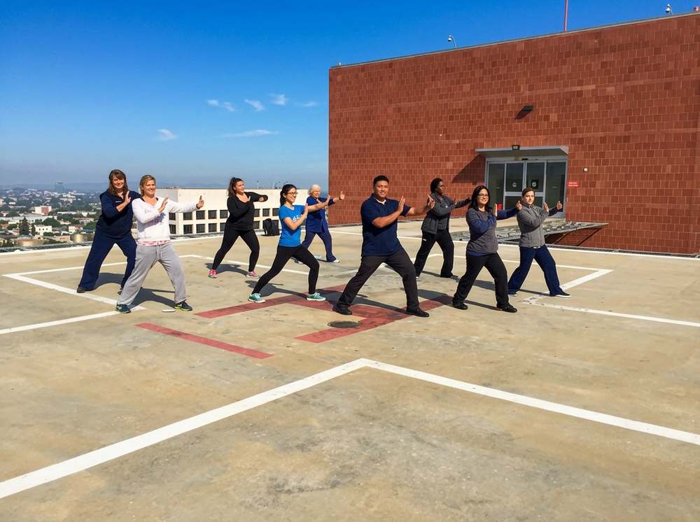 Marlon leading sunrise Tai Chi with healthcare providers on rooftop helipad